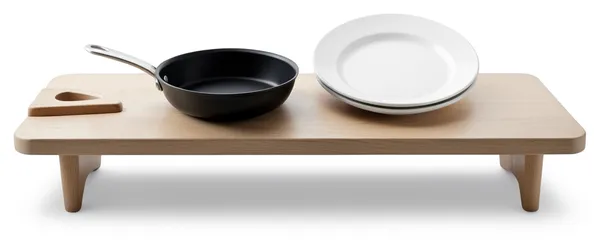 A board, a pan and a stack of plates laid out in order on one counter.