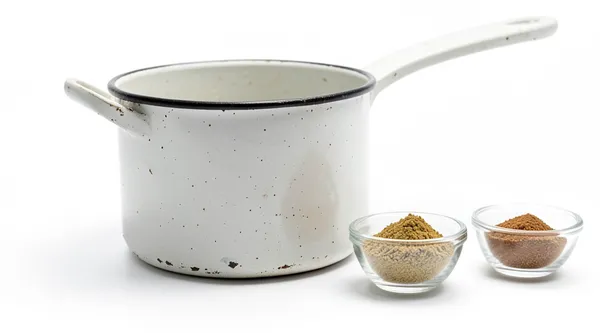 An old enamel pot beside two small bowls of spice blend.